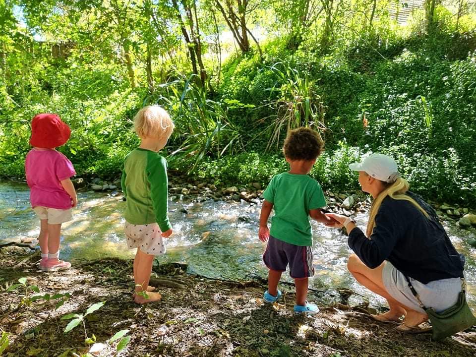 Outdoor play 4 A group of three children and their carer looking into a stream during outdoor play