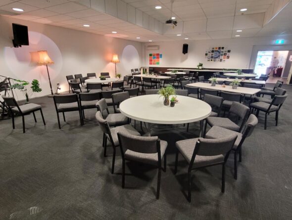 Conference Room Set Up With Plants On Round Tables, Dim Light And Lots Of Space