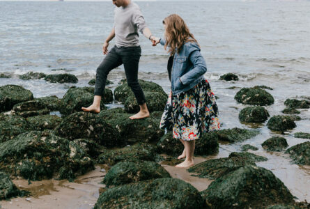 Couple With Contracting Out Agreement Holding Hands While Walking Over Beach Rocks