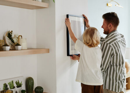 father and son hanging picture on wall